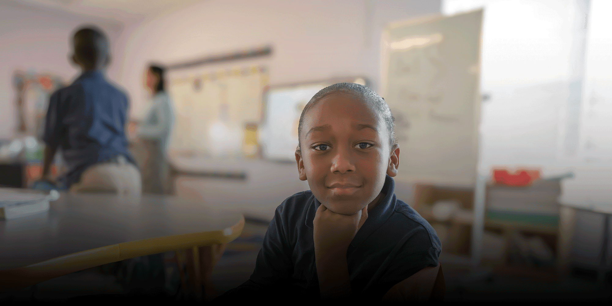 Student rests their chin on their hand at a classroom table.